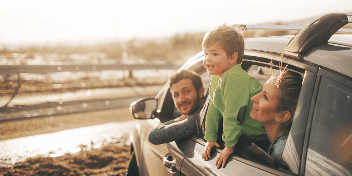 ouders met kind die uit het autoraam hangt