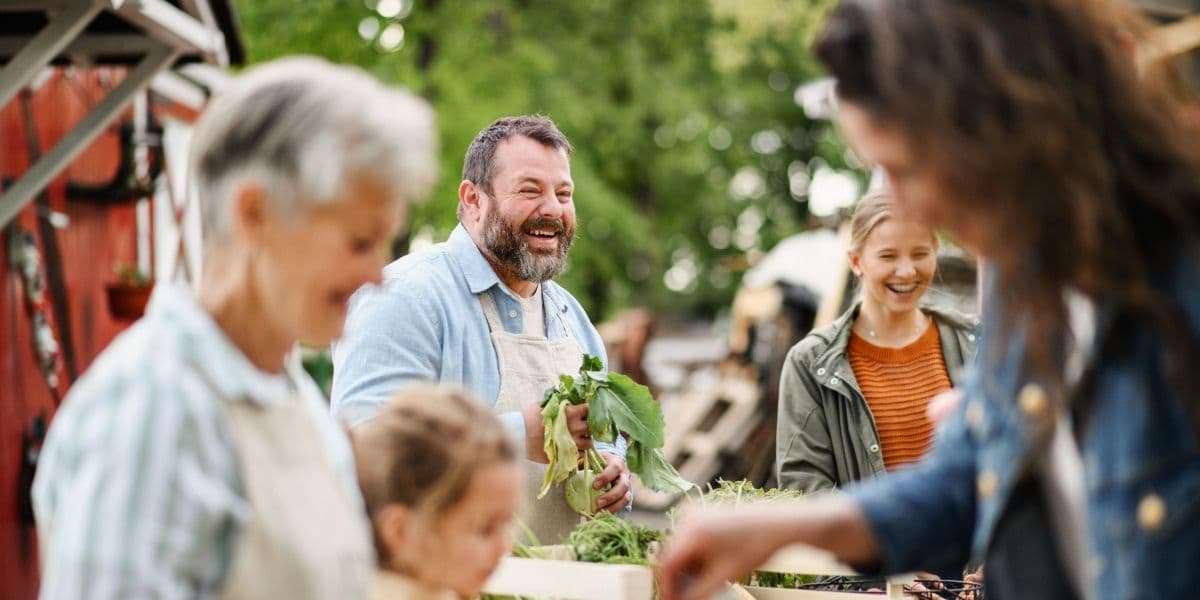 Man kijkt lachend naar de buren om hem heen terwijl het met eten in zijn handen staat