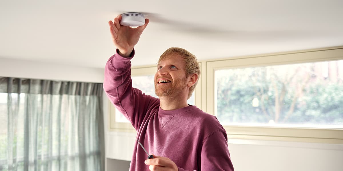 Man bevestigt een rookmelder aan het plafond