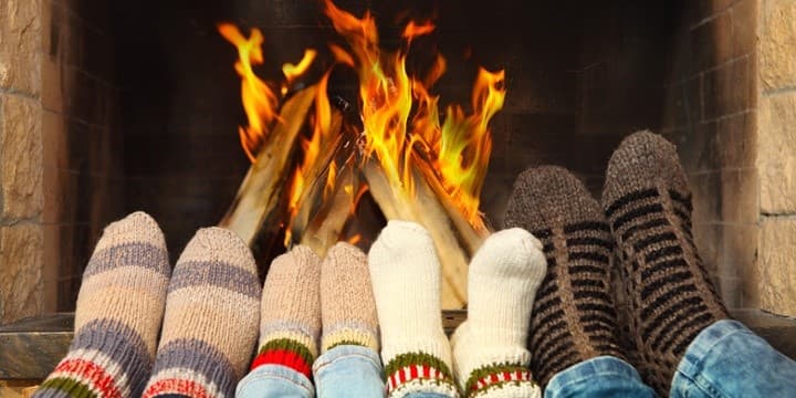 Vier paar voeten met dikke sokken liggen voor het haardvuur