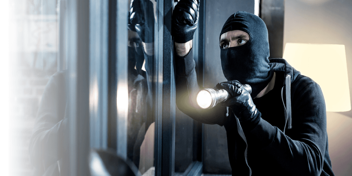 Inbreker met bivakmuts en zaklamp probeert een huis binnen te komen.