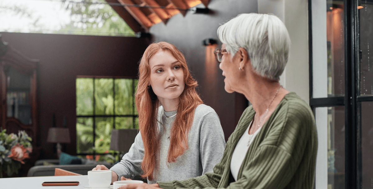 Twee vrouwen drinken samen koffie aan de keukentafel.