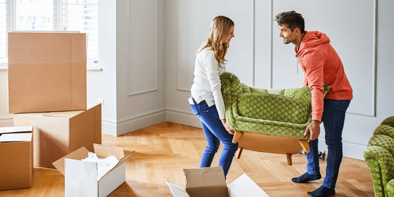 Een stel tilt stoel tijdens de verhuizing naar hun nieuwe woning. Verhuisdozen staan op de achtergrond.