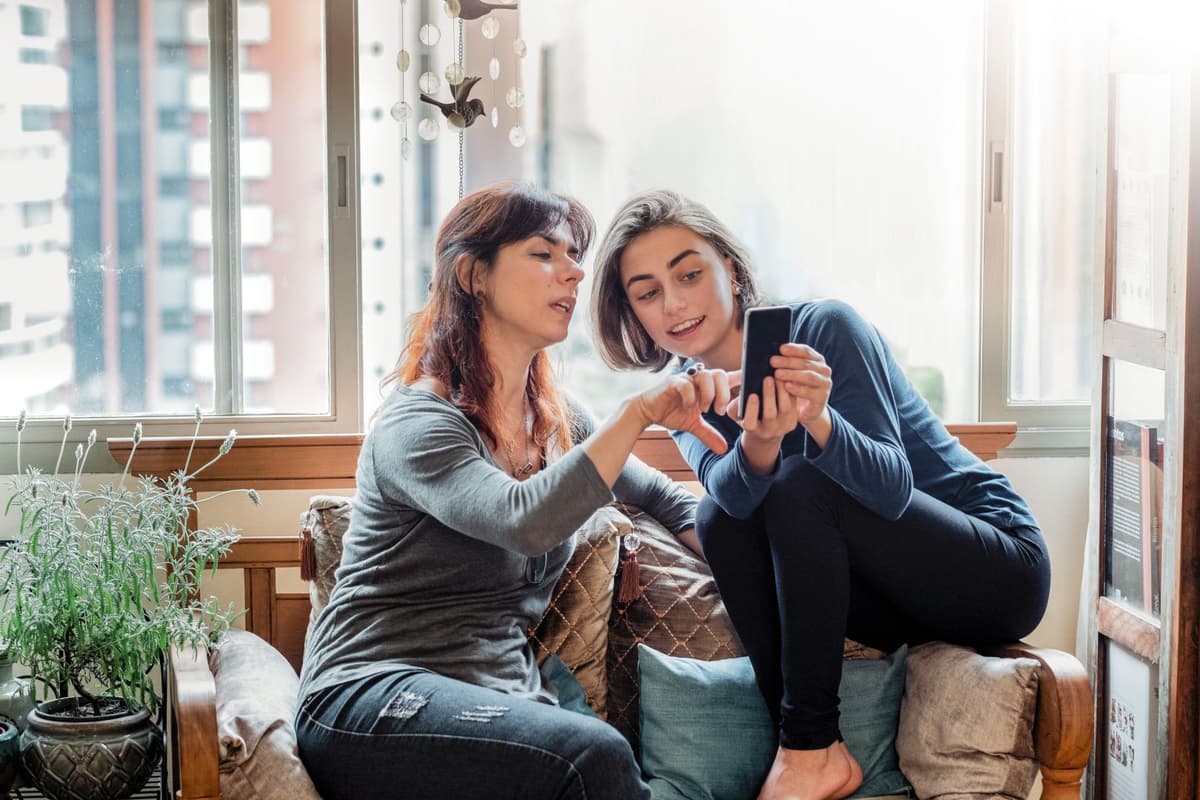 Twee vrouwen zitten in de woonkamer op een telefoon te kijken