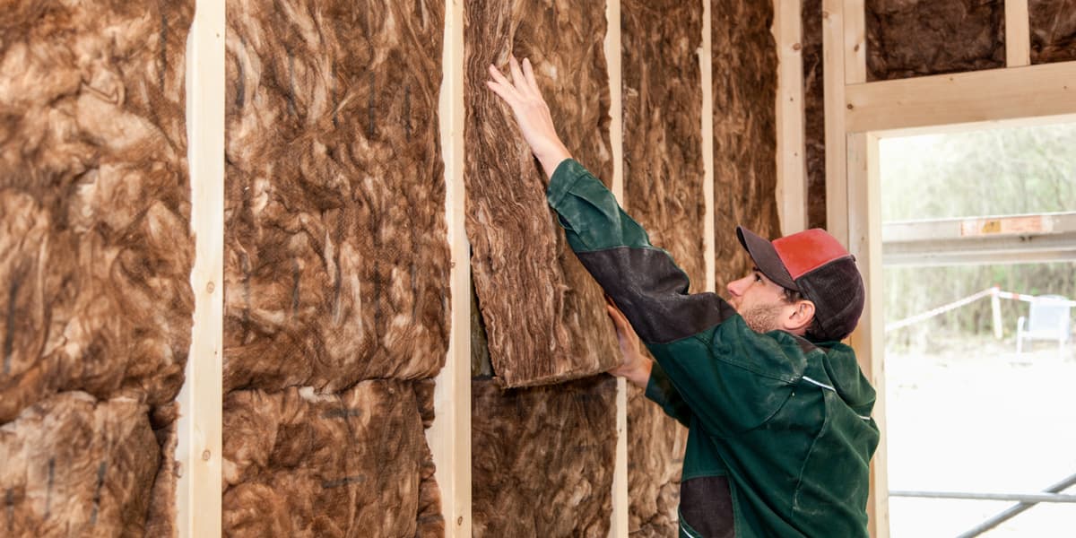 Man brengt isolatiemateriaal aan in een nieuwe tussenwand in een huis