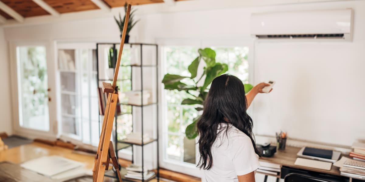 Vrouw zet airconditioning in de woonkamer aan met afstandsbediening