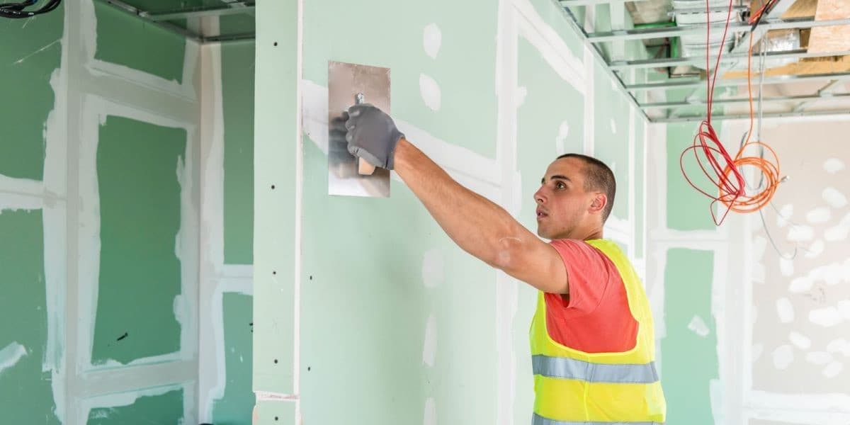 Een stukadoor stuct de naden van een muur gemaakt van gipsplaten