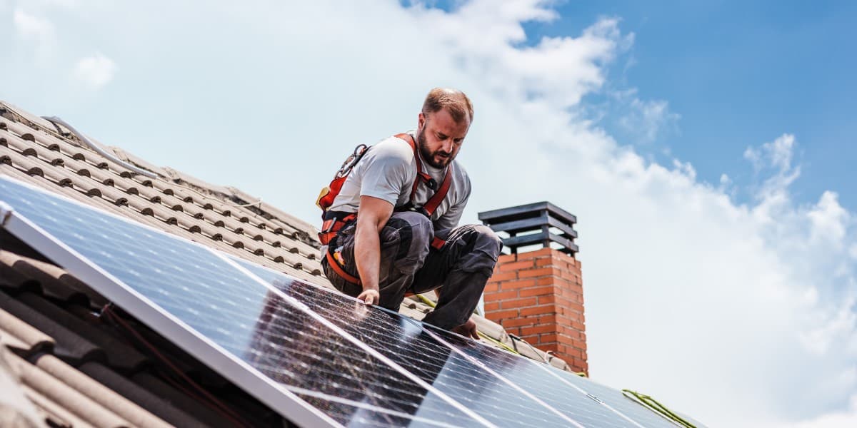 Man installeert zonnepanelen op het dak van een huurwoning