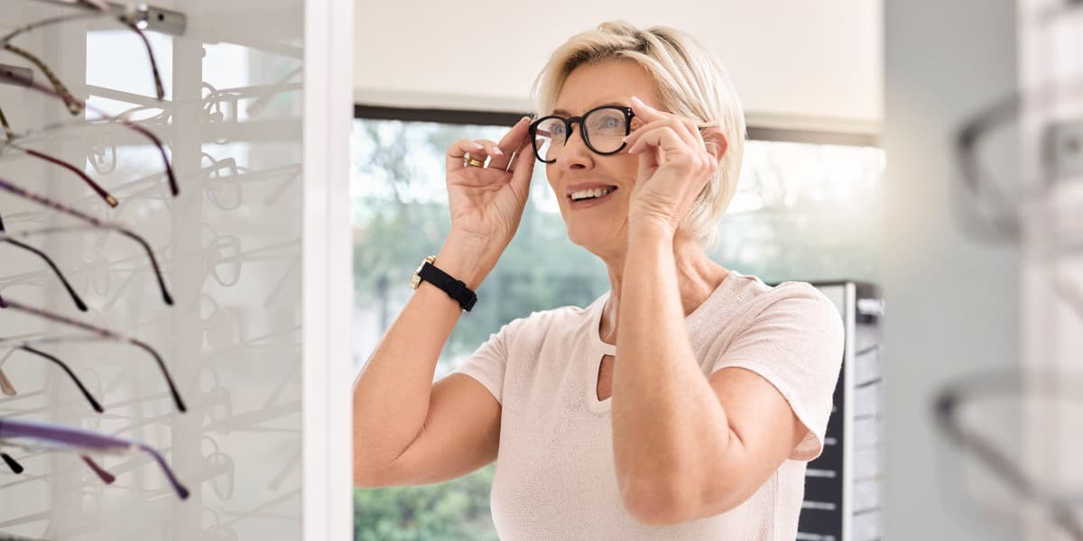 Een vrouw met kort haar past een bril in een brillenwinkel