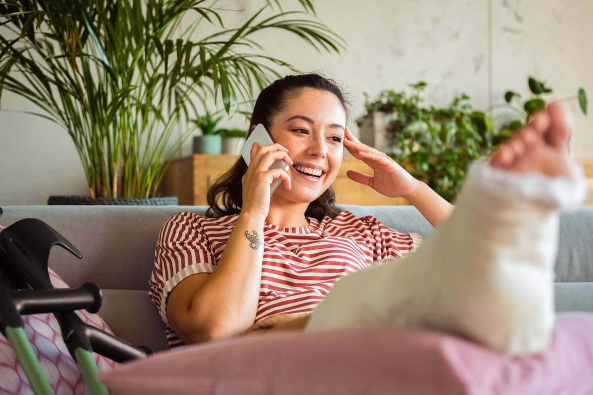 lachend aan de telefoon met voet in het gips