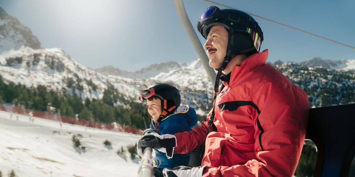 Vader en zoon samen in de skilift in een zonnig wintersportgebied