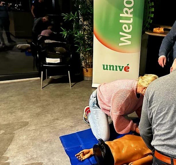 AED training op de grond met een banner van Univé op de achtergrond