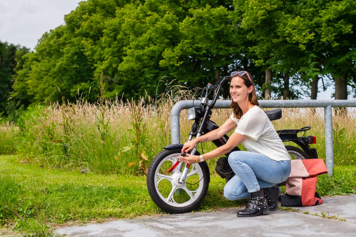 Vrouw die het slot bevestigd aan een bromfiets