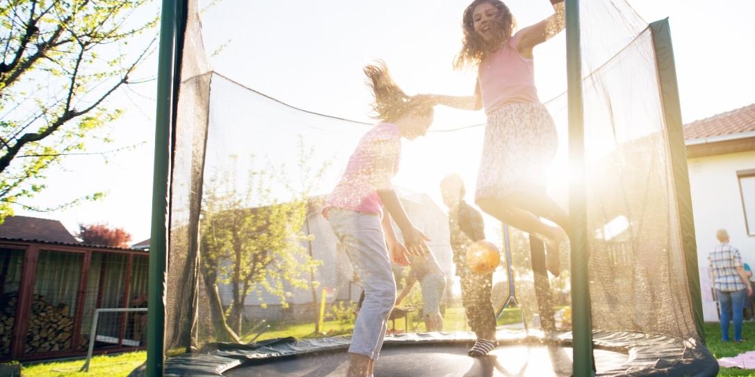 Kinderen springen op trampoline. Trampoline verzekerd bij stormschade