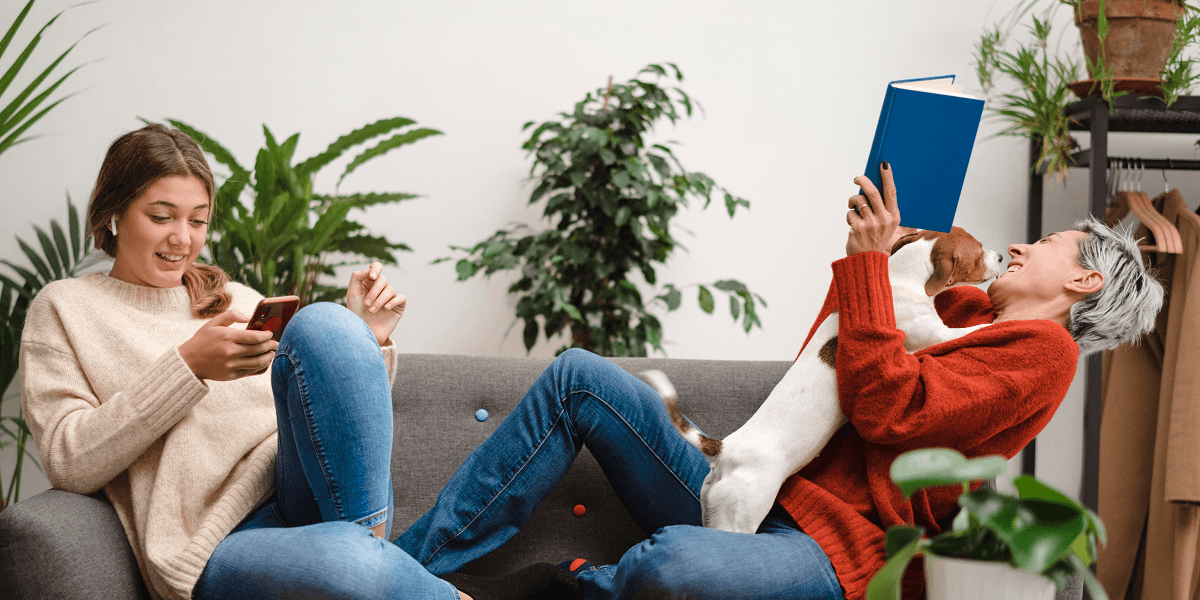 Moeder met dochter en hond op de bank en dochter is aan het bellen