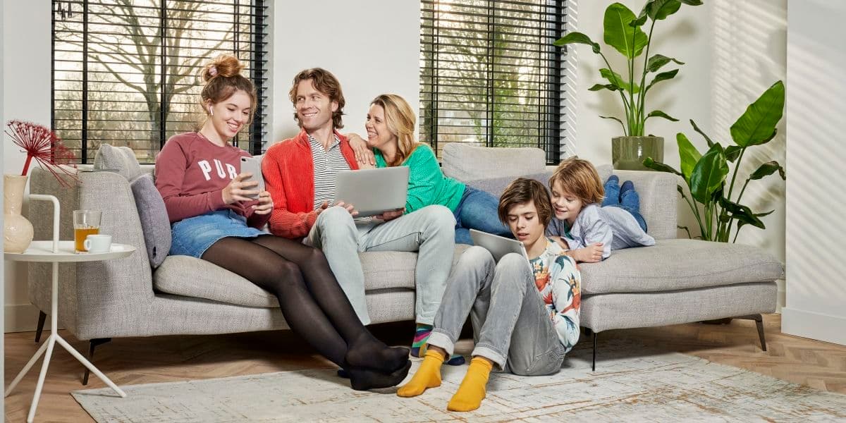 Gezin zit op de bank met een laptop en tablet