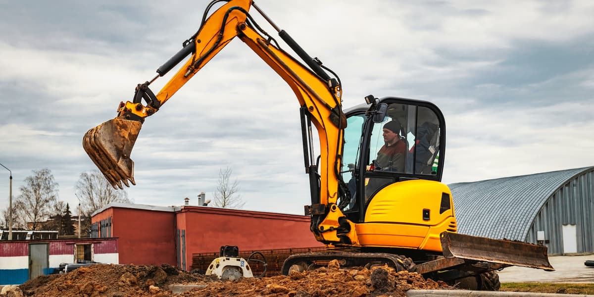 Man in graafmachine op de bouwplaats.