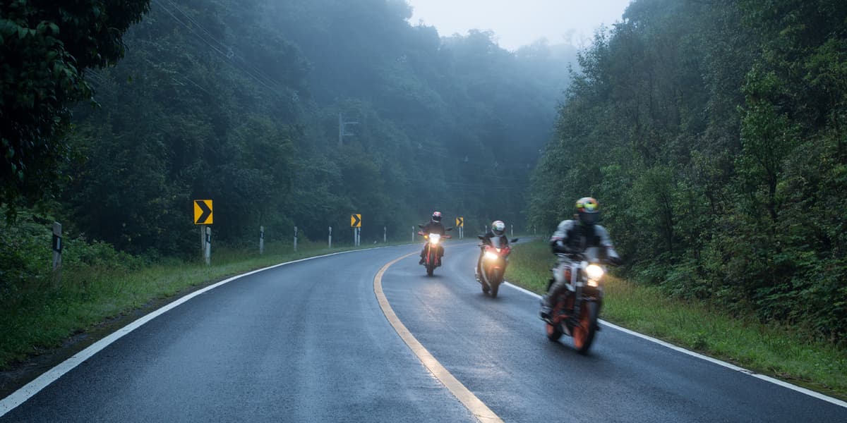 drie motorrijders rijden terwijl het regent en hard waait