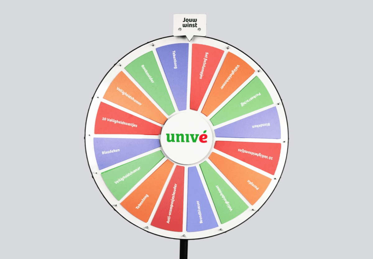 Een kleurrijk draaiwiel met het logo van Univé in het midden. Het wiel is verdeeld in vakken met verschillende preventieprijzen in het Nederlands, zoals "Rookmelder", "Veiligheidshamer", "Blusdeken", "10 Veiligheidsvestjes", en "Pompje". Het wiel heeft afwisselende kleuren per vak: rood, oranje, groen en paars. Bovenaan het wiel bevindt zich een aanwijzer die bepaalt welke prijs gewonnen wordt.