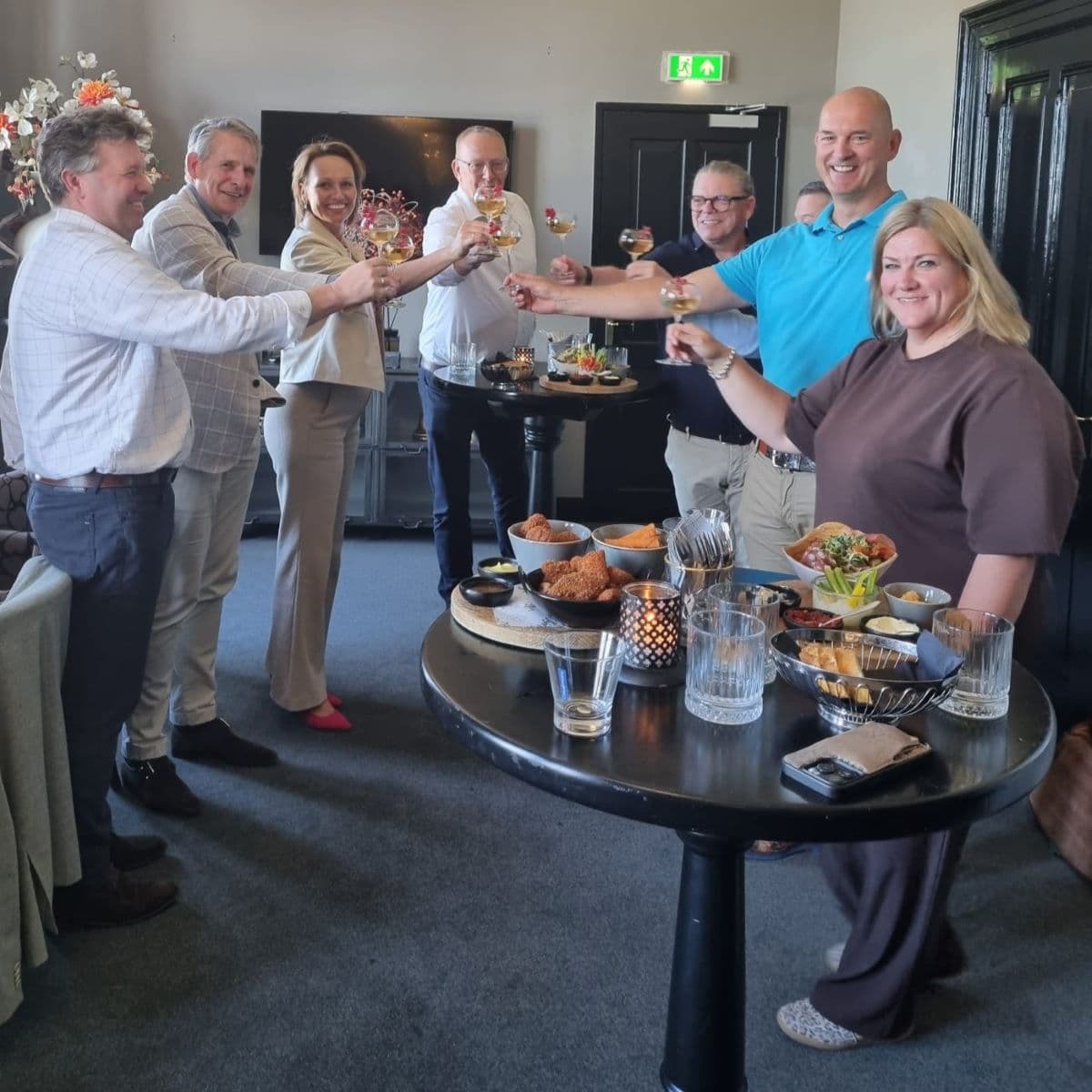 Advema en Unive Zuid-Nederland hebben de samenwerkingsovereenkomst getekend en heffen het glas. Van links naar rechts, Jacob Valkenburg, Francis en Brigitte (UZN), John Kopmels, Peter Krijgsman, Jan van Oord (deels zichtbaar), Leander Beerman en Rianne Korteweg.