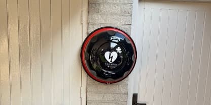 Een AED aan de muur onder de carport