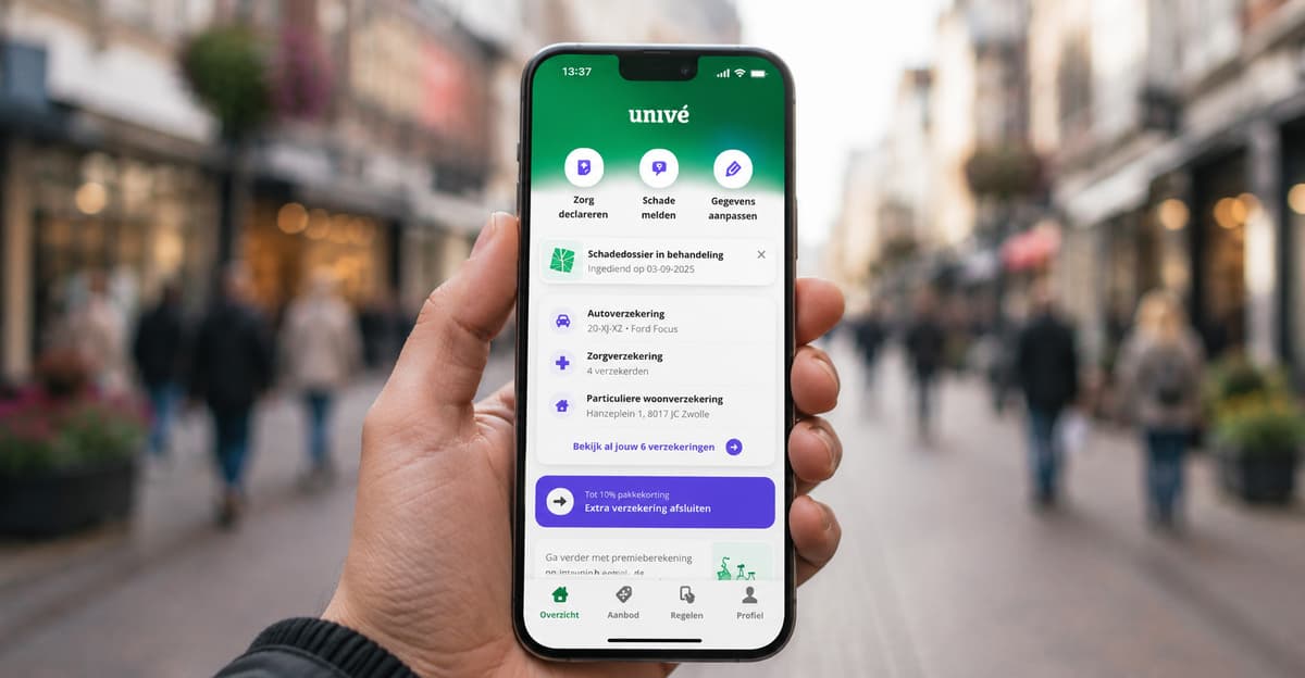 Hand houdt een smartphone vast met de Univé-app open. Op het scherm staan snelkoppelingen en een overzicht van verzekeringen en een lopend schadedossier, met op de achtergrond een onscherpe winkelstraat.