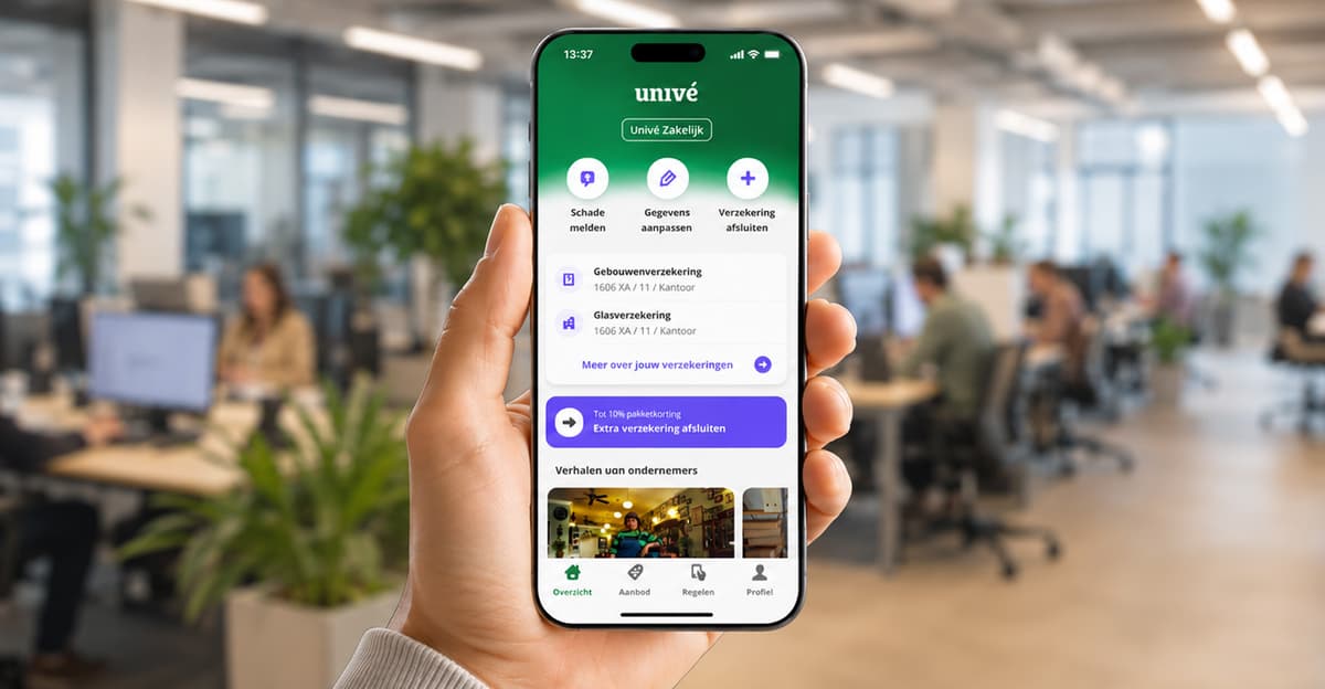 Hand houdt een smartphone vast met de Univé Zakelijk-app open. Op het scherm staan snelkoppelingen voor schade melden, gegevens aanpassen en verzekering afsluiten, plus een overzicht van zakelijke verzekeringen. Op de achtergrond is een onscherpe kantooromgeving met werkende mensen te zien.